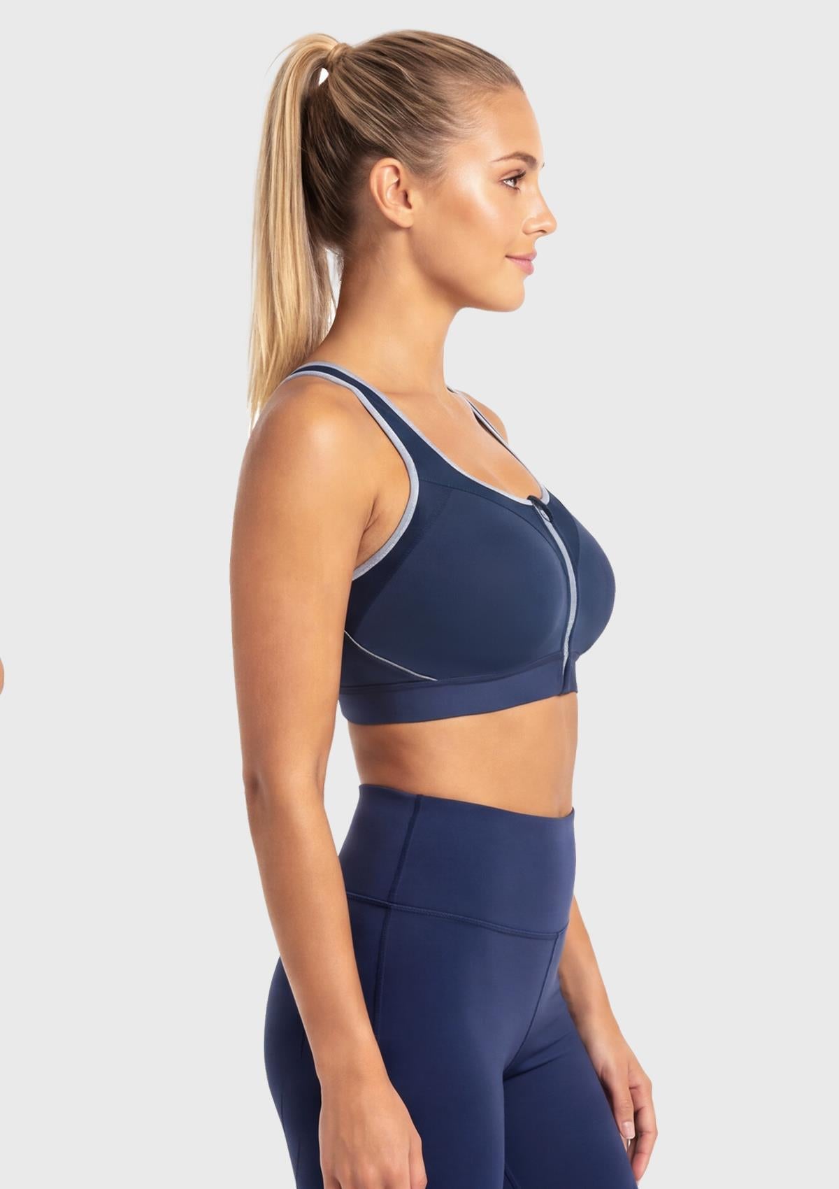 Side profile of the Dark Blue front zip running bra on model, showcasing the fixed molded cups that provide zero-bounce support and deep side coverage.