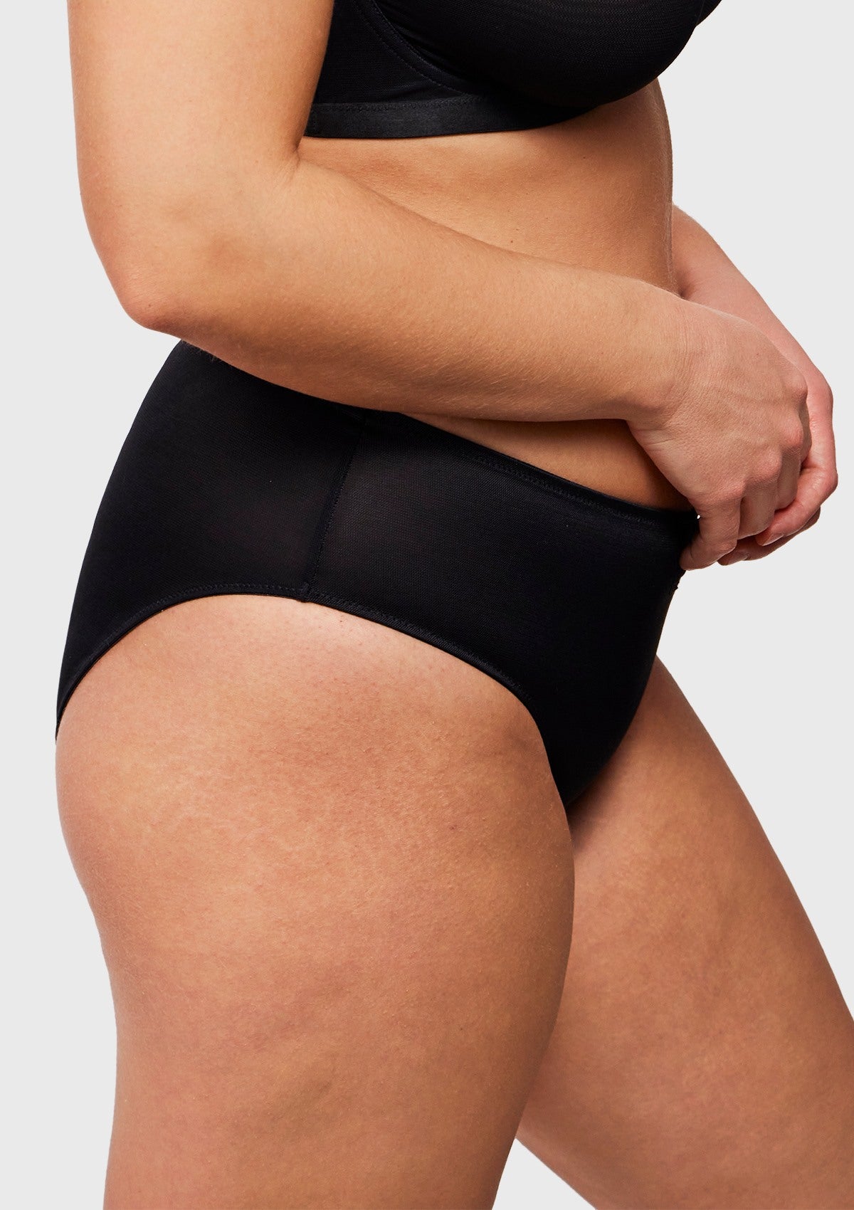 Side view of model wearing black Bella sheer mesh panties, highlighting high-cut leg openings and seamless comfort.