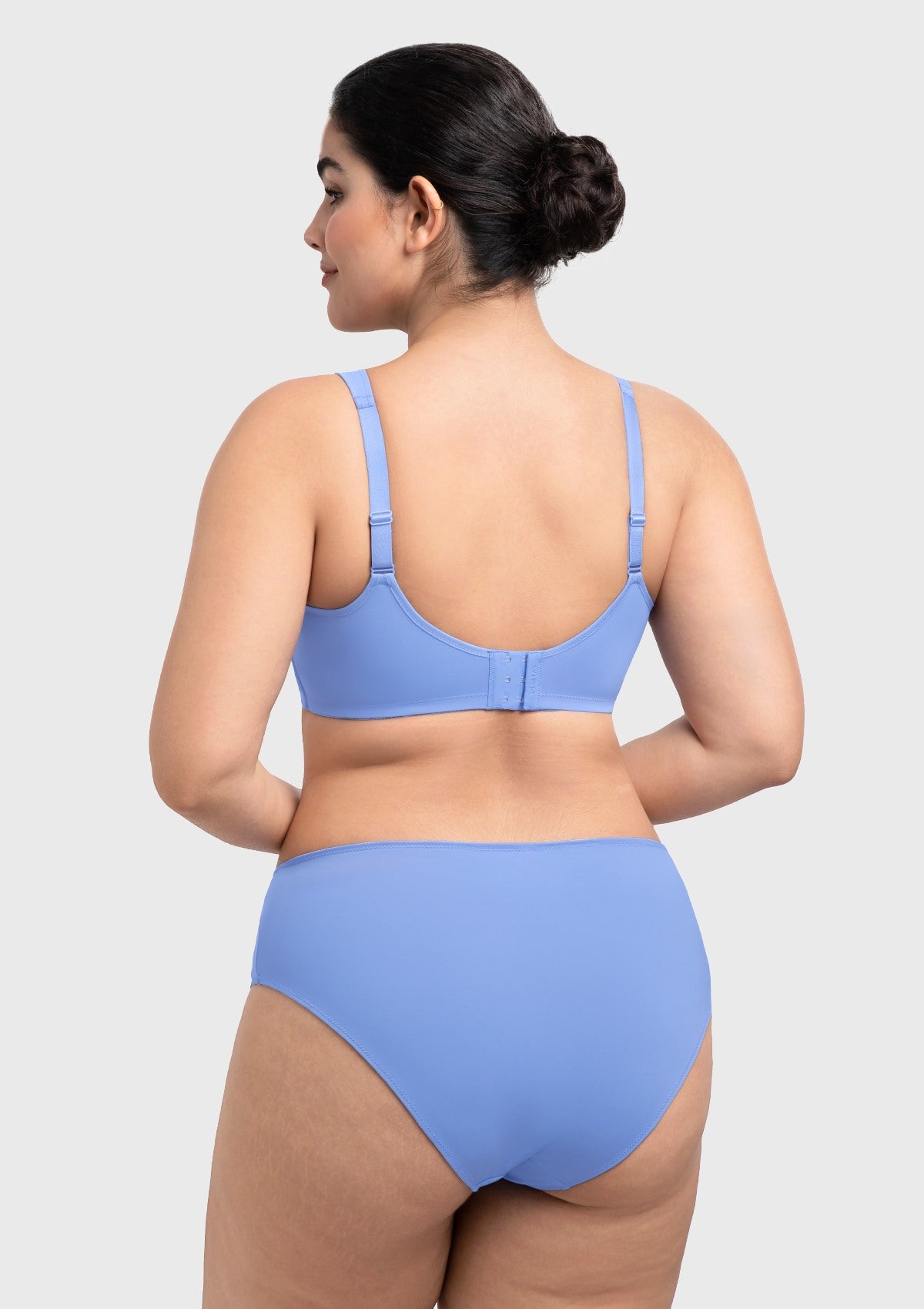 Rear view of the sky blue seamless back smoothing bra, designed with laser-cut edges to remain completely invisible under silk blouses.